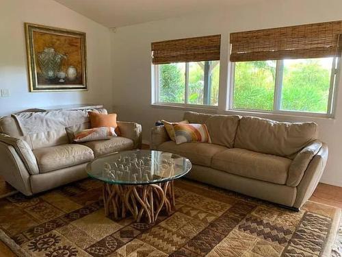 a living room with a couch and a glass table at Peaceful Olinda Getaway in Makawao