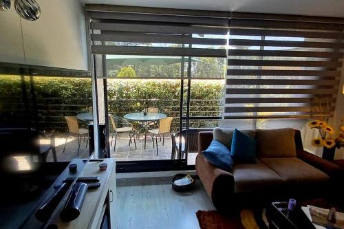 a living room with a couch and a patio with a table at Acogedor Apartamento Loft en Club House en Cajicá in Cajicá
