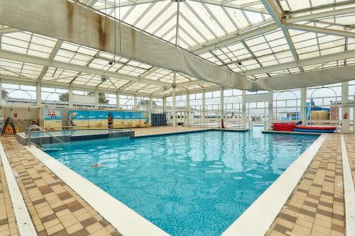 a large swimming pool with blue water in a building at California Breeze in Scratby