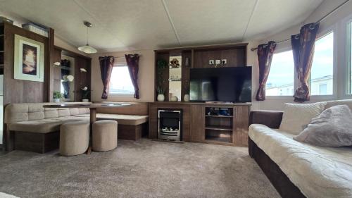 Una sala de estar con un sofá y un televisor de pantalla plana. en California Breeze, en Scratby