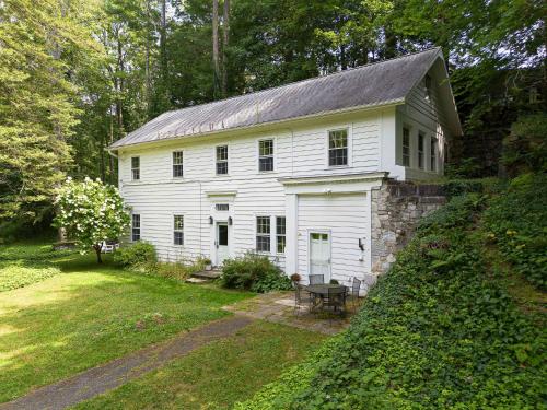 an old white house with a stone wall at Berkshire Vacation Rentals 1900s Factory Turned Modern Berkshires Retreat in Great Barrington