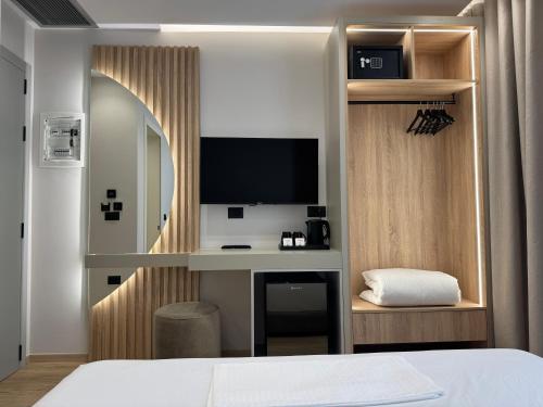 a bedroom with a bed and a desk with a television at Erdeti Boutique Hotel in Sarandë