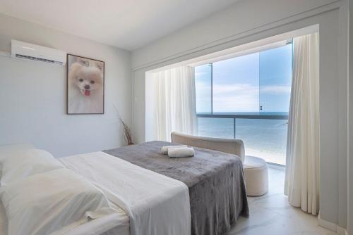 a bedroom with a bed with a table and a window at IPTZ160- Frente mar c/ vista incrível do 16º andar in Balneário Camboriú
