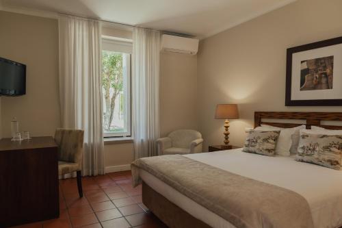 a bedroom with a bed and a window at Quinta do Pinheiro Hotel E Eventos by Grupo Quinta dos Lagos in Valado dos Frades