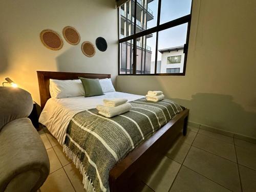 Un dormitorio con una cama con toallas. en Serene Studio - Steps away Rosebank Mall, en Johannesburgo