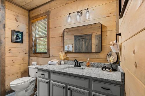 a bathroom with a sink and a toilet and a mirror at The Spirit Bear Lodge by American Patriot Getaways in Glade