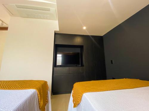 a bedroom with two beds and a tv on the wall at Maidy Luxury Hotel in Medellín