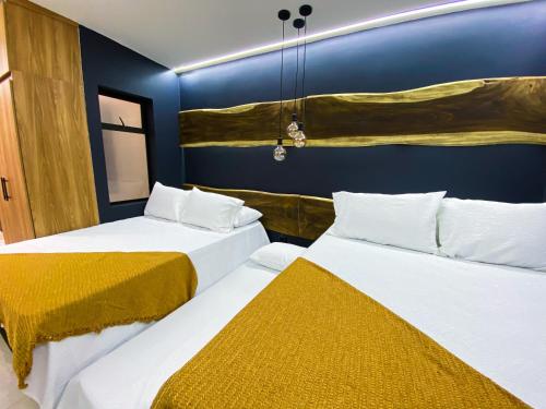 two beds in a room with blue walls at Maidy Luxury Hotel in Medellín