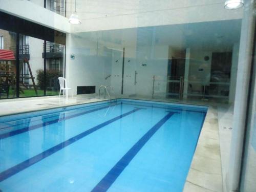 a large swimming pool with blue water in a building at Acogedor Apartamento Loft en Club House en Cajicá in Cajicá