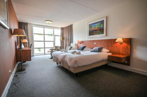 a hotel room with a large bed and a window at De Stobbe hotel & suites in Ruinen
