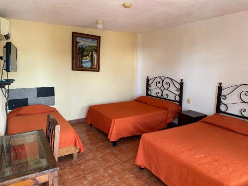 a room with two beds with orange sheets at Microhotel Ciudad del Carmen in Ciudad del Carmen
