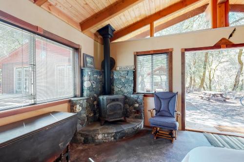 a living room with a wood stove and a chair at Hawkins Bar River Home in Hawkins Bar