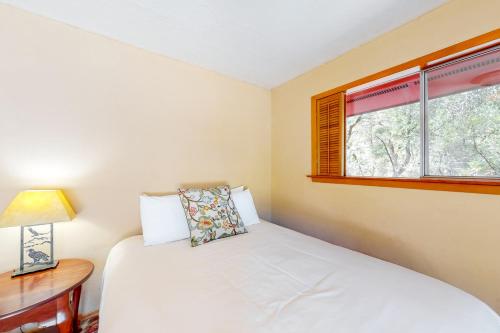 a bedroom with a bed and a desk and two windows at Hawkins Bar River Home in Hawkins Bar
