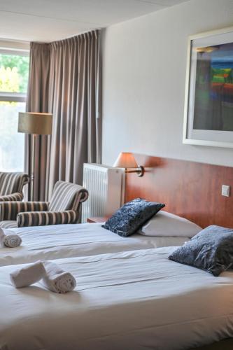 a hotel room with two beds and a window at De Stobbe hotel & suites in Ruinen