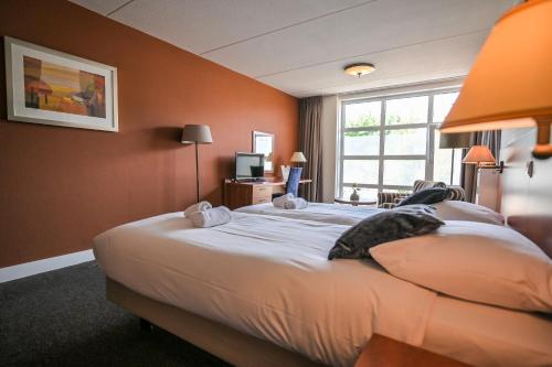 a bedroom with a large white bed with a window at De Stobbe hotel & suites in Ruinen