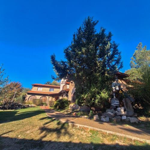 a house with a tree and a statue in the yard at Hotel Antiguo Camino in Villa General Belgrano