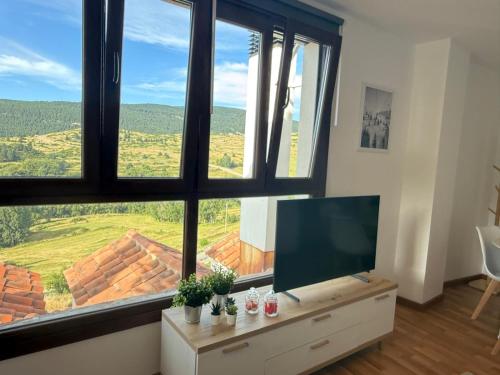 a living room with a flat screen tv and large windows at el mirador de ona in Valdelinares