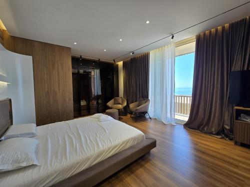 a bedroom with a bed and a large window at Modern Luxury Villa in Green Coast with Sea View & Private Garden in Llogara