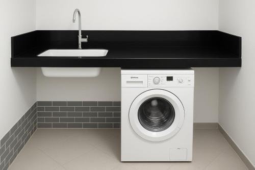 a kitchen with a sink and a washing machine at Villa Malkia's in Enaboishu