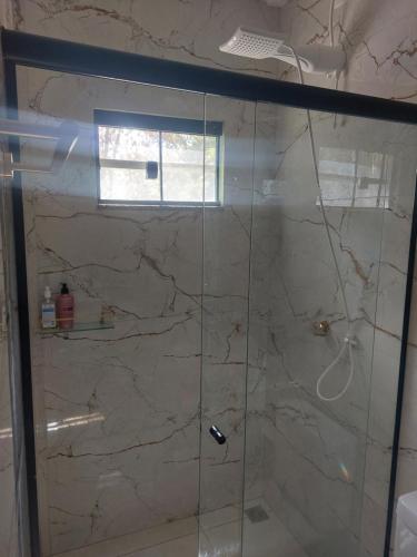 una ducha con puerta de cristal en un baño en Chalé na lata, en Pirenópolis