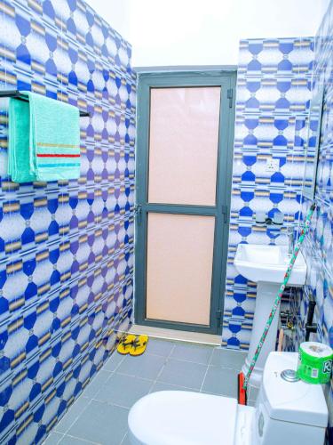 a bathroom with blue and white tiled walls and a toilet at Nungwi Modern Apartment 2 in Kinyasini
