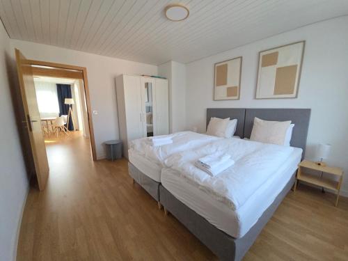 a bedroom with a large bed with white sheets at Apartment for 5, close to Zurich and Luzern, free private parking in Wohlen