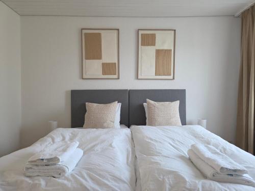 a bedroom with two beds with white sheets and towels at Apartment for 5, close to Zurich and Luzern, free private parking in Wohlen