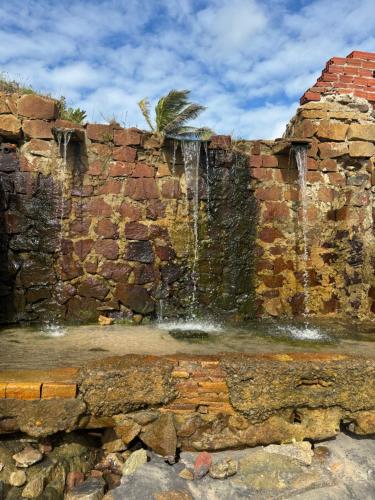 a stone wall with a water fountain at Casa Cochilo na Rede in Beberibe