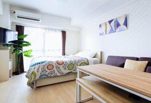 a room with a bed and a couch and a table at MIYAVI#303 3min walk Narimasu Station, 4 people, wide queen bed & sofa, Tokyo's largest Don Quijote in Tokyo