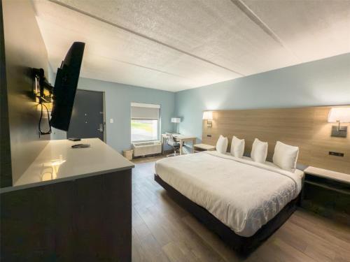 a bedroom with a bed and a desk with a television at SureStay by Best Western Jacksonville Airport in Jacksonville