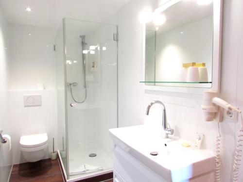 a white bathroom with a sink and a shower at Feuriger Tatzlwurm Berghotel & Spa, BW Signature Collection in Oberaudorf