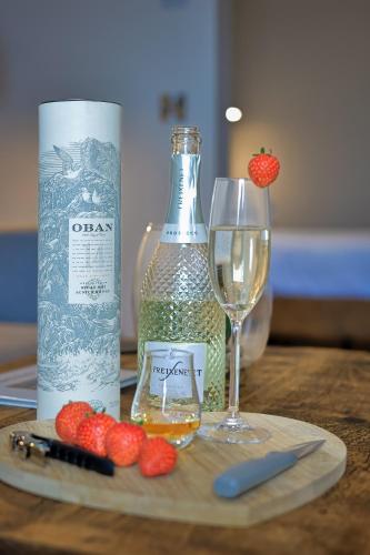 a bottle of alcohol and a glass of wine and strawberries at Oban Bay Apartments in Oban