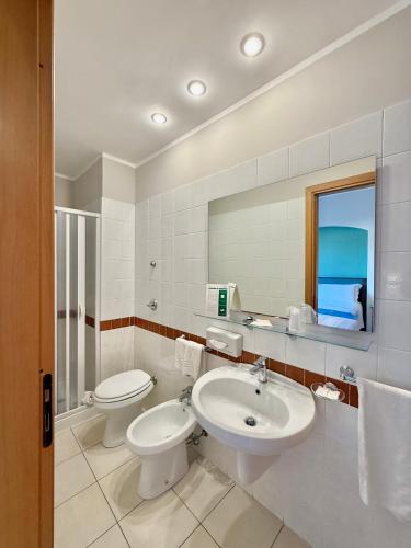 a bathroom with a sink and a toilet and a mirror at Hotel Panoramic in San Vito lo Capo