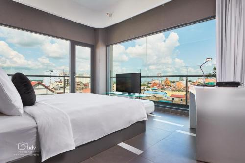 a bedroom with a large bed and a large window at SUN & MOON, Urban Hotel in Phnom Penh