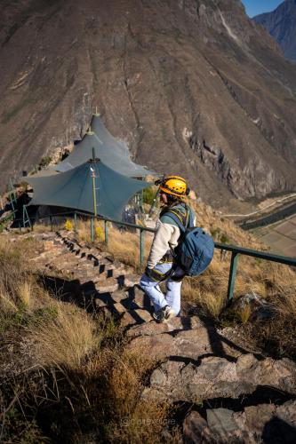 a man walking up a hill with a tent at Vertical Sky Suites in Ollantaytambo