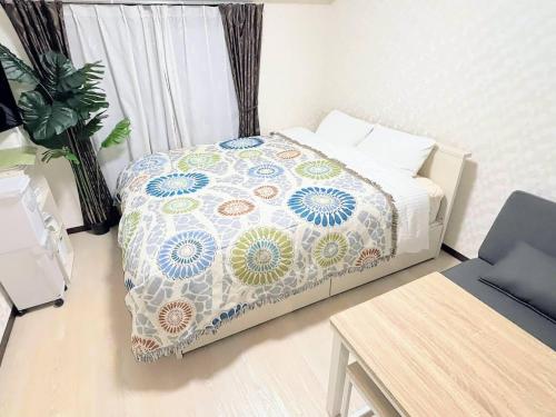 a small bedroom with a bed with a flowered blanket at MIYAVI#303 3min walk Narimasu Station, 4 people, wide queen bed & sofa, Tokyo's largest Don Quijote in Tokyo