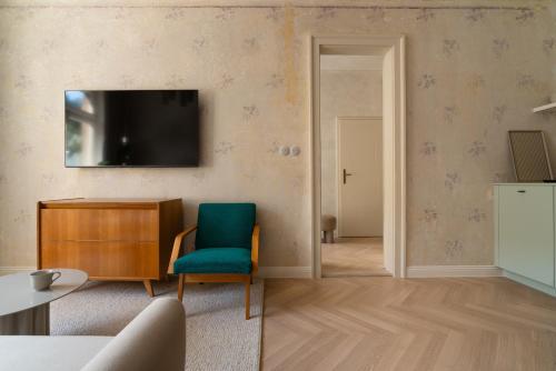 sala de estar con silla azul y TV en Limewash Apartments Karlsbad, en Karlovy Vary