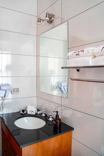 a bathroom with a sink and a mirror and towels at Mamasara Machupicchu in Machu Picchu