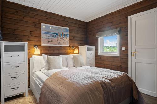 a bedroom with wooden walls and a bed and a window at Fagertoppen 1314B by Vacation Trysil in Mælem