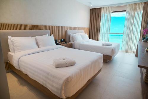 a hotel room with two beds and a large window at MantaHost Hotel in Manta