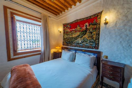 a bedroom with a bed with a painting on the wall at RIAD LA SANTA in Chefchaouene