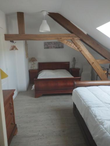 a attic bedroom with a bed and a dresser at La fermette de Chandigon in Antran