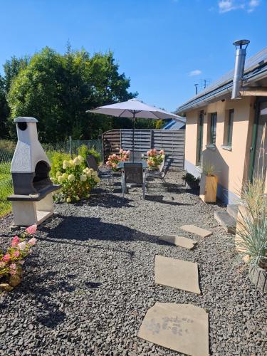 a patio with an umbrella and a table and a bench at Agroturystyka u Kozdryka in Leśna