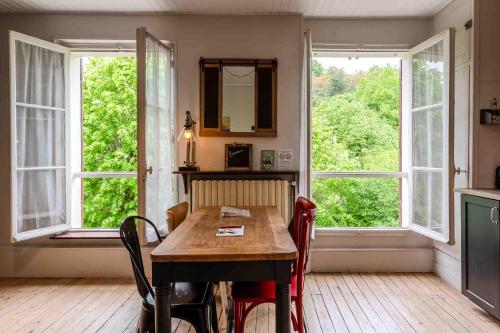 a dining room with a table and two windows at Marquise Barbot in Evry-Courcouronnes
