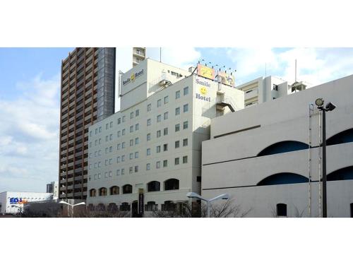 a large white building in front of tall buildings at Smile Hotel Shimonoseki - Vacation STAY 96732v in Shimonoseki