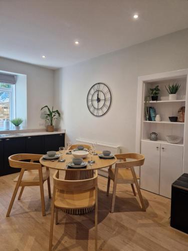 a dining room with a table and chairs and a clock at City Residence Free Parking in Stirling