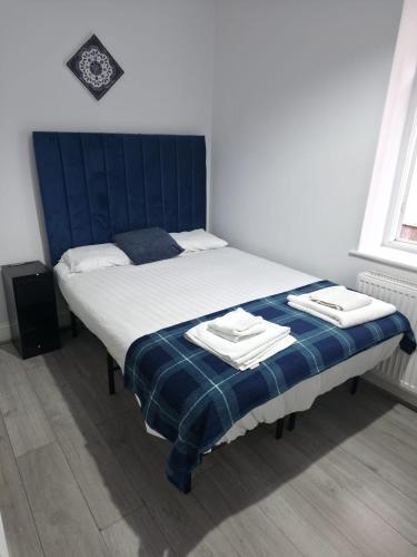 a bed in a bedroom with a blue headboard at Golders Park Hotel in London