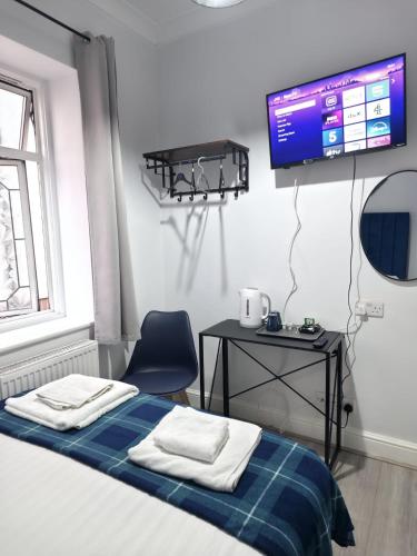 a bedroom with a bed and a table and a tv at Golders Park Hotel in London