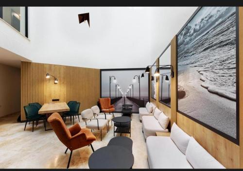 a waiting room with white furniture and a large painting at Baltic Waves SPA Apartament de lux A112 in Międzyzdroje