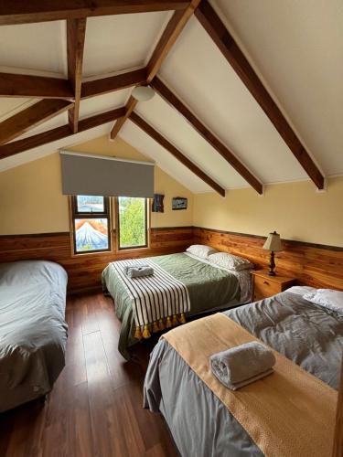 two beds in a room with wooden floors and ceilings at Cabañas Estacion del Lago in Puerto Varas